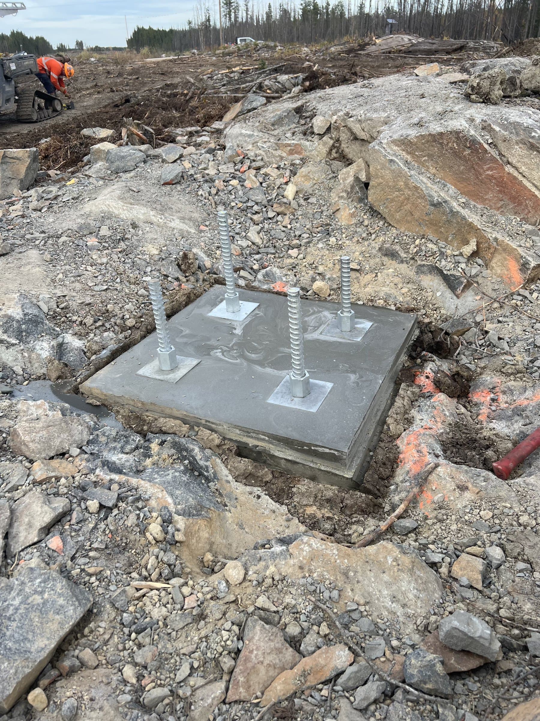 Anchor bolts set in a finished grout pad on a rocky transmission site