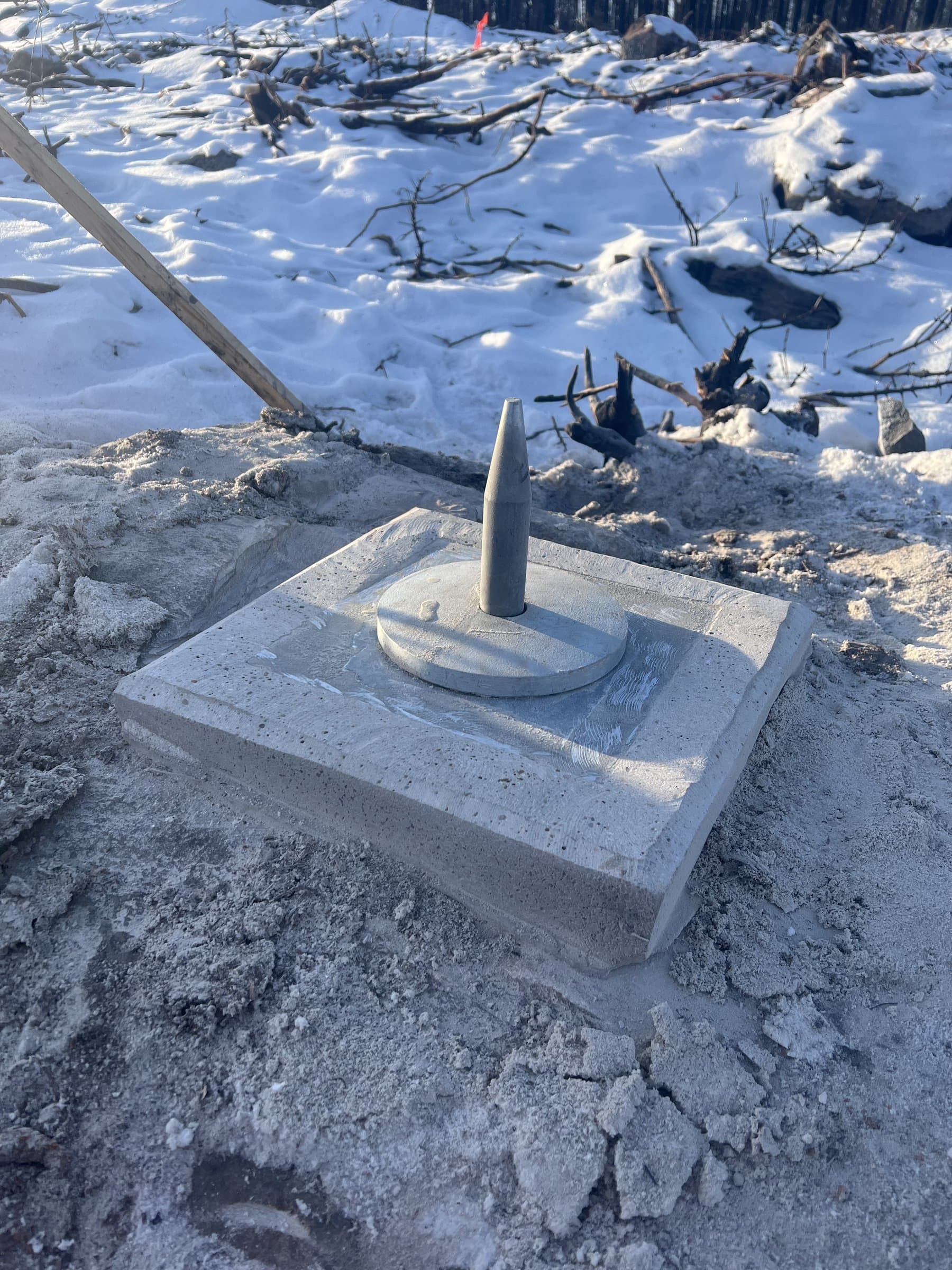 Completed grout pad with center anchor pin in winter field conditions